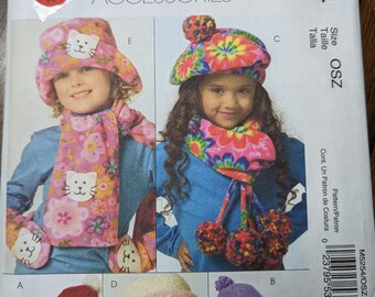 Può includere: Un cartamodello per cappelli e sciarpe per bambini. Il cartamodello comprende quattro modelli diversi: un cappello rosa con un viso di gatto, un cappello blu con un motivo floreale, un cappello rosa con un fiocco e un cappello viola con un motivo a forma di cuore. Il cartamodello è per la taglia OSZ ed è di McCall's Fashion Accessories.