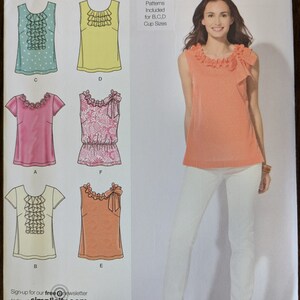 May include: A sewing pattern for a sleeveless top with a ruffled neckline. The pattern includes five different views, with variations in the neckline, sleeve length, and fabric. The pattern is for sizes D5 4, 6, 8, 10, 12, EUR 30-38, FR 32-40. Separate patterns are included for B, C, and D cup sizes.