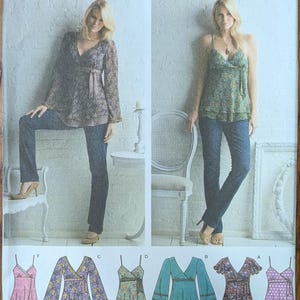 May include: A Simplicity 3956 sewing pattern envelope for a wrap-style top with various sleeve and print options. The package displays two models wearing different versions of the top with jeans, alongside six illustrated variations labeled A through F.