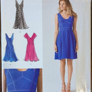 May include: A sewing pattern for a dress with a V-neck and sleeveless design. The pattern includes three different styles: a black and white patterned dress, a blue dress, and a pink dress. The pattern is from Simplicity and is for sizes 4-12.