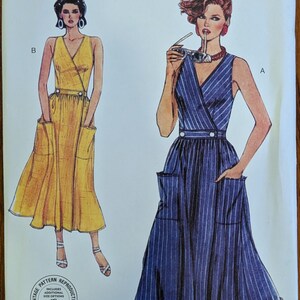May include: Vogue Patterns V2193 sewing pattern envelope for sizes 6-8-10-12-14. The cover features illustrations of two sleeveless wrap dresses with V-necklines, waistbands with buttons, and large patch pockets. One dress is yellow, the other is blue with white pinstripes.