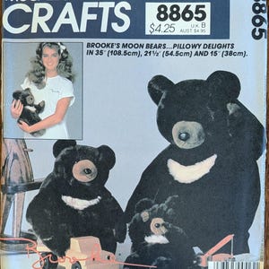 May include: McCall's Crafts sewing pattern 8865 for Brooke's Moon Bears, featuring three sizes: 35 inches, 21.5 inches, and 15 inches. The package displays a photograph of a person holding a bear and illustrations of black bears with white crescent chest markings.