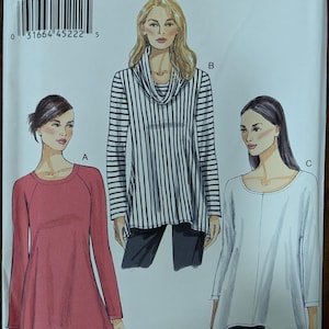 May include: Very Easy Vogue sewing pattern V8952 featuring three tunic tops. The pattern includes a red raglan sleeve top, a black and white striped cowl neck top, and a white boat neck top. The pattern is designed and printed in the USA.