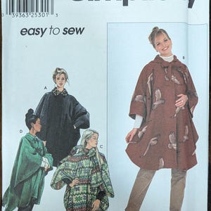 May include: Simplicity sewing pattern number 9864 for a one-size cape. The pattern includes four different styles of capes: a black cape, a green cape, a patterned cape, and a brown cape with a bird print. The pattern is labeled "easy to sew".