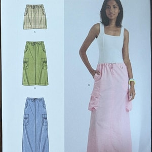 May include: Simplicity sewing pattern S9891 featuring three skirt designs. The pattern includes sizes U.S. 16-24. The image shows a woman wearing a pink skirt with pockets, a white top, and pink platform sandals.