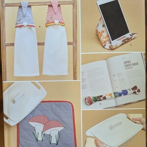 May include: Simplicity sewing pattern R11985 featuring instructions for hanging kitchen towels, a tablet stand, a draft stopper, a quilted pot holder with mushroom embroidery, and a casserole dish cover. The pattern is labeled as one size.