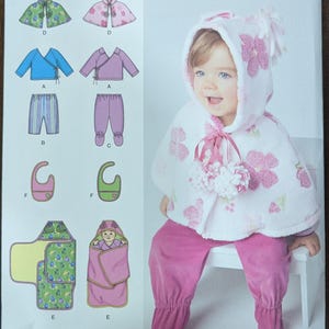 May include: A Simplicity sewing pattern for a baby's hooded cape, pants, top, and bib. The pattern includes instructions for sizes XXS-L. The pattern is illustrated with a baby wearing the cape and pants.