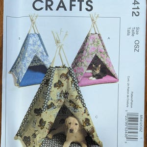 May include: McCall's Crafts M5412 sewing pattern envelope for pet teepees. The cover displays three fabric tent designs: one blue floral, one pink floral with a cat, and one dog-print fabric with a puppy on a paw-print cushion.