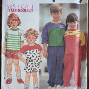 May include: Simplicity sewing pattern 7942 for children's clothing. The pattern features illustrations of children in various outfits, including shorts, t-shirts, and pants. The text "YES I CAN LEARN TO SEW" is visible on the pattern.