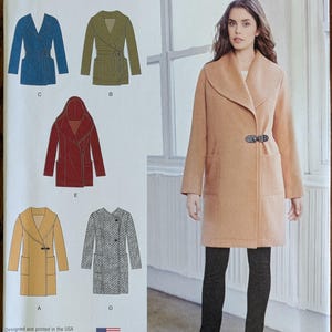 May include: Simplicity 1067 sewing pattern envelope featuring illustrations of five coat variations in blue, olive, red, yellow, and gray. The front displays a tan coat with a wide collar and toggle closure, size U.S. 6-14, printed and designed in the USA.