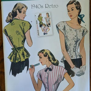 May include: Simplicity sewing pattern 1590 H5 for 1940s retro tops in sizes 6-14. The envelope features illustrations of three different short-sleeved blouse styles, including a green floral print, a white floral print, and a pink and white striped version.