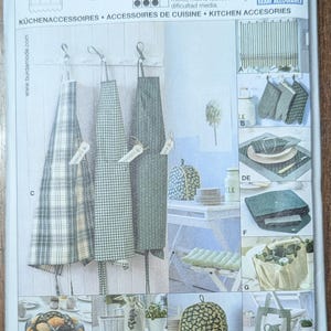 May include: A sewing pattern package labeled "8125" with images of kitchen accessories. The package features aprons in various patterns, including plaid and striped designs. Additional images showcase items like pot holders and tea cozies.