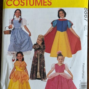 May include: A McCall's Costumes pattern envelope featuring images of children in various costume designs. The costumes include a blue gingham dress, a yellow dress, a Snow White dress, and a pink princess dress. The envelope is yellow with red and white text.