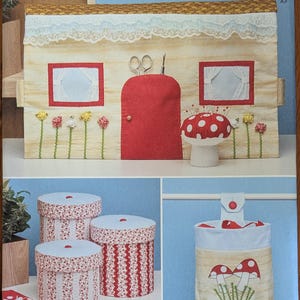 May include: A Simplicity S9587 sewing pattern envelope featuring a house-shaped fabric organizer with a red door, a red and white polka dot mushroom pincushion, three round fabric-covered storage boxes, and a hanging bag with mushroom motifs.