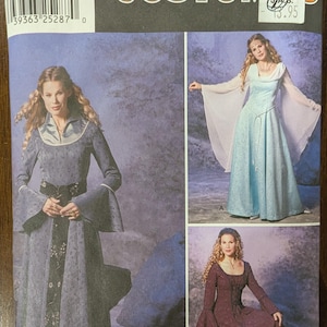 May include: Simplicity Costumes sewing pattern for a medieval style gown. The pattern includes two different styles, one with a long, flowing skirt and the other with a shorter skirt. The pattern is for sizes 14, 16, 18, and 20.