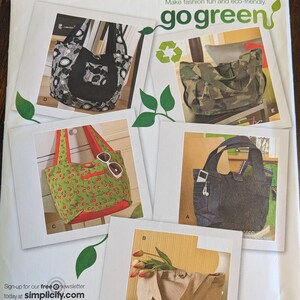 May include: A Simplicity sewing pattern for making five different tote bags. The pattern is titled "go green" and includes instructions for making a black and white tote bag, a camouflage tote bag, a red and green tote bag with cherries, a blue denim tote bag, and a beige tote bag.