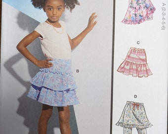 Può includere: Cartamodello McCall's M8316 per gonne e pantaloncini da bambina. Il modello include più opzioni di visualizzazione con semplici istruzioni. L'immagine mostra una ragazzina che indossa una gonna dal modello. Il modello è progettato e stampato negli Stati Uniti.