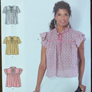 May include: Simplicity sewing pattern S9546, featuring a woman wearing a paisley print top. The pattern includes options for different blouse styles. The text "easy-to-sew" is visible. Sizes U.S. 4-16 are indicated.