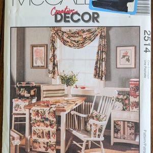 May include: A McCall's Creative Decor sewing pattern envelope featuring a room scene with a wooden table, white chairs, and floral curtains. The pattern number is 2514. The scene includes framed artwork and decorative storage boxes.