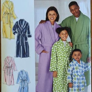 May include: Simplicity 562 A @Home easy-to-sew pattern envelope featuring illustrations of four robe styles in yellow, dark blue, pink, and light blue. The cover displays a photograph of four individuals wearing a lavender, green, polka dot, and plaid robe.