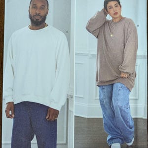 May include: Simplicity sewing pattern S9897 featuring two models wearing a white sweatshirt and a brown sweatshirt with blue jeans. The pattern includes sizes XS-XXL. The text "easy-to-sew" is visible.