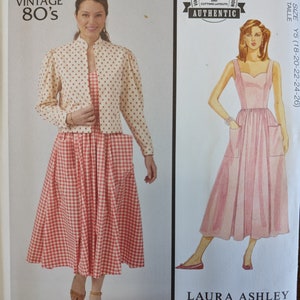 May include: Vintage McCall's sewing pattern for a dress with a gingham print and a matching jacket. The pattern is from the 1980s and is a reproduction of a Laura Ashley design. The pattern includes additional size options and cutting layouts.