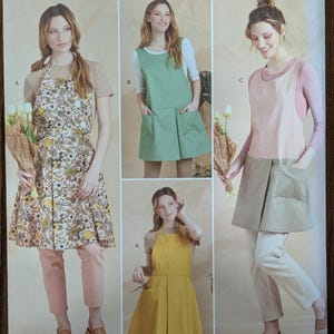 May include: Simplicity sewing pattern S9564 featuring aprons in various styles. The aprons are shown in different colors and patterns, including floral, solid green, pink, and yellow. The pattern includes sizes XS-XL.