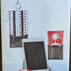 May include: Simplicity pattern S9514 featuring various fabric projects. The image showcases a tablet, a red and white patterned pouch, and a black leather-like pouch with a red and white patterned interior. The pattern is designed and printed in the USA.