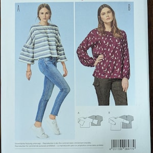 May include: A sewing pattern for blouses, featuring two blouse designs. The pattern includes sizes EUR 32-44 and US 6-18. The image shows a woman wearing a striped blouse and another in a burgundy floral blouse.