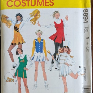 May include: A vintage McCall's Costumes pattern envelope. The yellow cover features illustrations of cheerleaders and a marching band member in various outfits. The pattern number is 8894, size B (8, 10, 12).