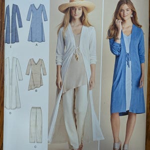 May include: Simplicity pattern 8059 for a long-sleeved duster, dress, and pants. The envelope displays illustrations of the garments and photographs of models wearing a white duster over a beige top and pants, and a blue duster over a white dress.
