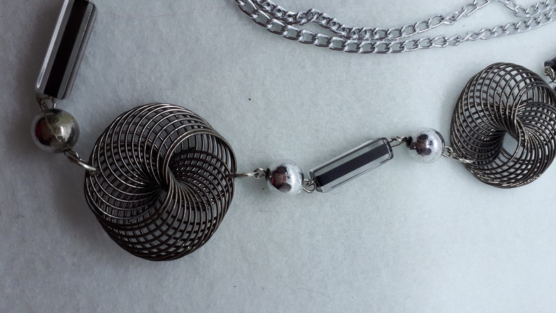 3 twisted wire embellishments. Silvertone chain necklace with silver beads acrylic beads