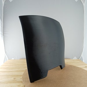 May include: A black 3D printed object with a curved shape and a flat base. The object has a small opening on the back.