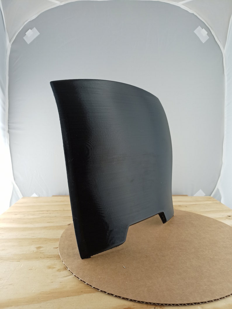 May include: A black 3D printed object with a curved shape and a flat base. The object has a small opening on the back.