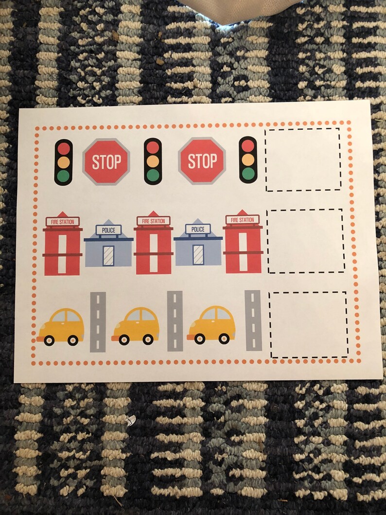 May include: A printable activity sheet for kids featuring a town scene with fire stations, police stations, traffic lights, stop signs, cars, and roads. The sheet includes blank spaces for drawing or writing.