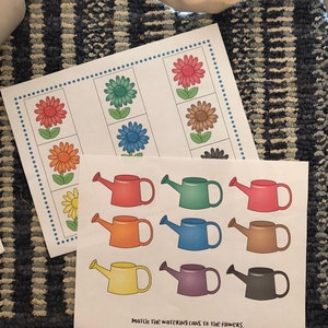 May include: A printable educational activity for kids featuring a matching game with colorful flowers and watering cans. The text "Match the watering cans to the flowers" is printed at the bottom of the page.