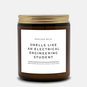 May include: A brown glass candle jar with a gold lid. The label reads "Smells like an electrical engineering student" and "Herayus Drive". The candle is hand-poured vegan soy coconut wax.