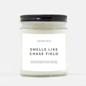May include: A white candle in a clear glass jar with a black lid. The label reads "Smells Like Chase Field" and "Mercury Drive".