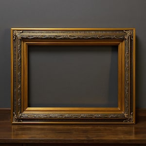 May include: Ornate gold-colored picture frame with detailed carvings. The rectangular frame has a dark brown border and a lighter gold interior. The frame is displayed on a wooden surface against a dark gray background.