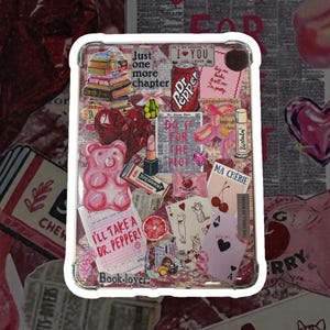 May include: A clear phone case with a pink, red, and white collage of stickers. The stickers include a Dr. Pepper can, a cherry, a gummy bear, a book stack, a lipstick, and the text "Just one more chapter" and "I'll take a Dr. Pepper!"