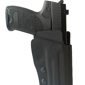 Op de afbeelding: Een zwart pistool met een zwarte holster. De holster heeft twee zwarte schroeven aan de zijkant.