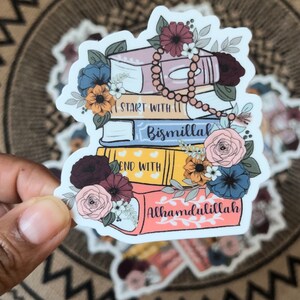 May include: A sticker with a stack of books decorated with flowers and a string of beads. The books have the words "Start with Bismillah" and "End with Alhamdulillah" on them.