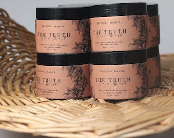 May include: Six black jars of face mask powder labeled "Original Manna The Truth Face Mask" with a floral design on the label. The jars are in a wicker basket.