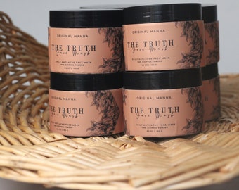 May include: Six black jars of face mask powder labeled "Original Manna The Truth Face Mask" with a floral design on the label. The jars are in a wicker basket.