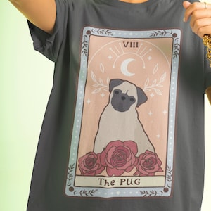 Può includere: Una maglietta grigia scura con un design di carta dei tarocchi con un carlino, rose e il testo "The PUG" e "VIII".