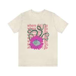 May include: A cream coloured t-shirt with a pink flower with an eye in the centre. The flower is surrounded by green vines and the text "where did I go" is repeated in pink.