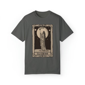 Op de afbeelding: Een donkergrijs T-shirt met een vintage tarotkaartontwerp. De kaart toont een vrouw in een lange jurk die een kelk vasthoudt. De kaart is gelabeld met "VIII The BRIDE".