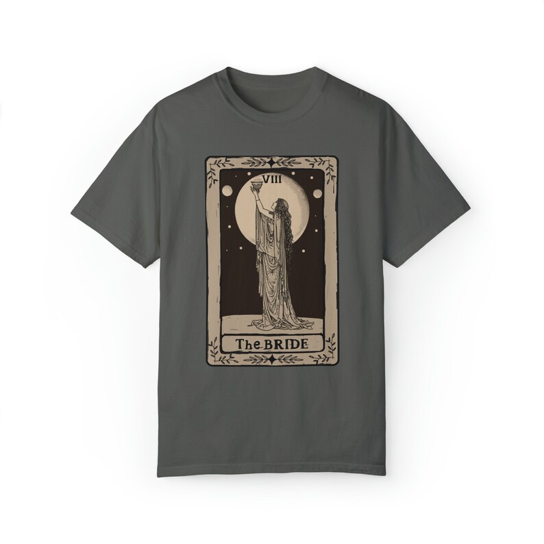Op de afbeelding: Een donkergrijs T-shirt met een vintage tarotkaartontwerp. De kaart toont een vrouw in een lange jurk die een kelk vasthoudt. De kaart is gelabeld met "VIII The BRIDE".