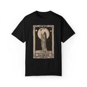 Op de afbeelding: Zwart T-shirt met een vintage tarotkaartontwerp met een vrouw die een kelk vasthoudt. De kaart is gelabeld "VIII The BRIDE".