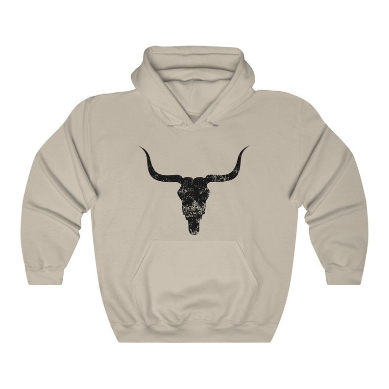 Pu&ograve; includere: Una felpa con cappuccio beige con una grafica di teschio di toro nero invecchiato sul davanti.